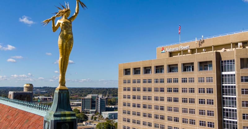 A technician inspecting residential rooftop solar panels with a battery storage unit nearby.