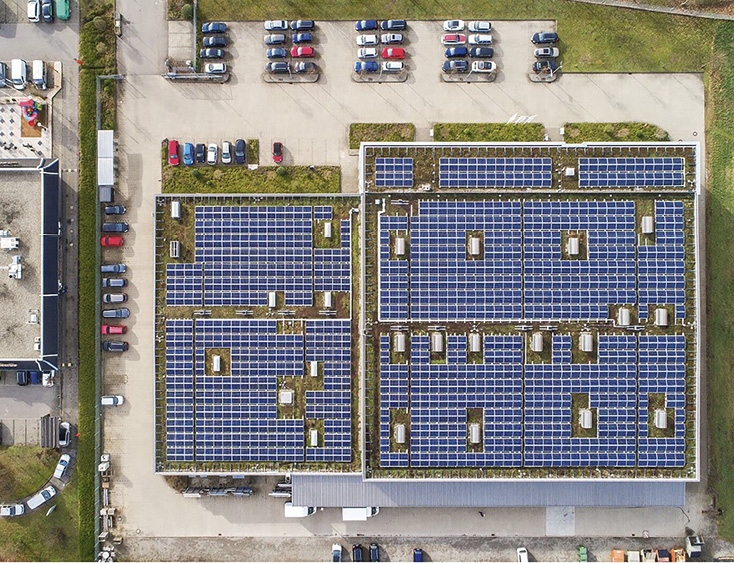 Aerial view of a massive industrial rooftop solar installation in a European city