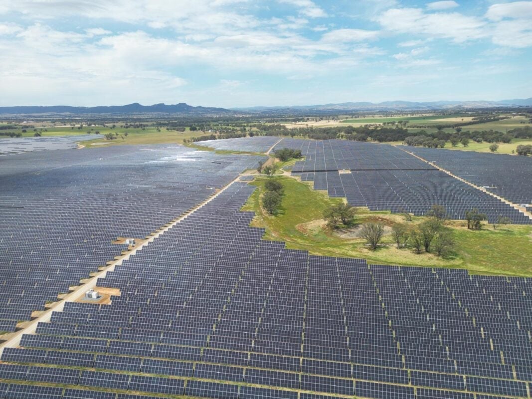 Large scale utility solar farm with thousands of monocrystalline panels under a clear sky.