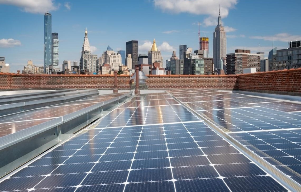 Large scale community solar array installed on a flat commercial rooftop in an urban environment.