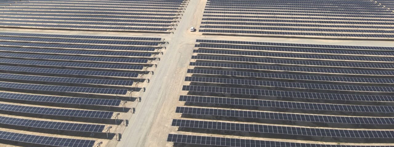 Large scale utility solar plant in desert terrain with integrated battery storage units.