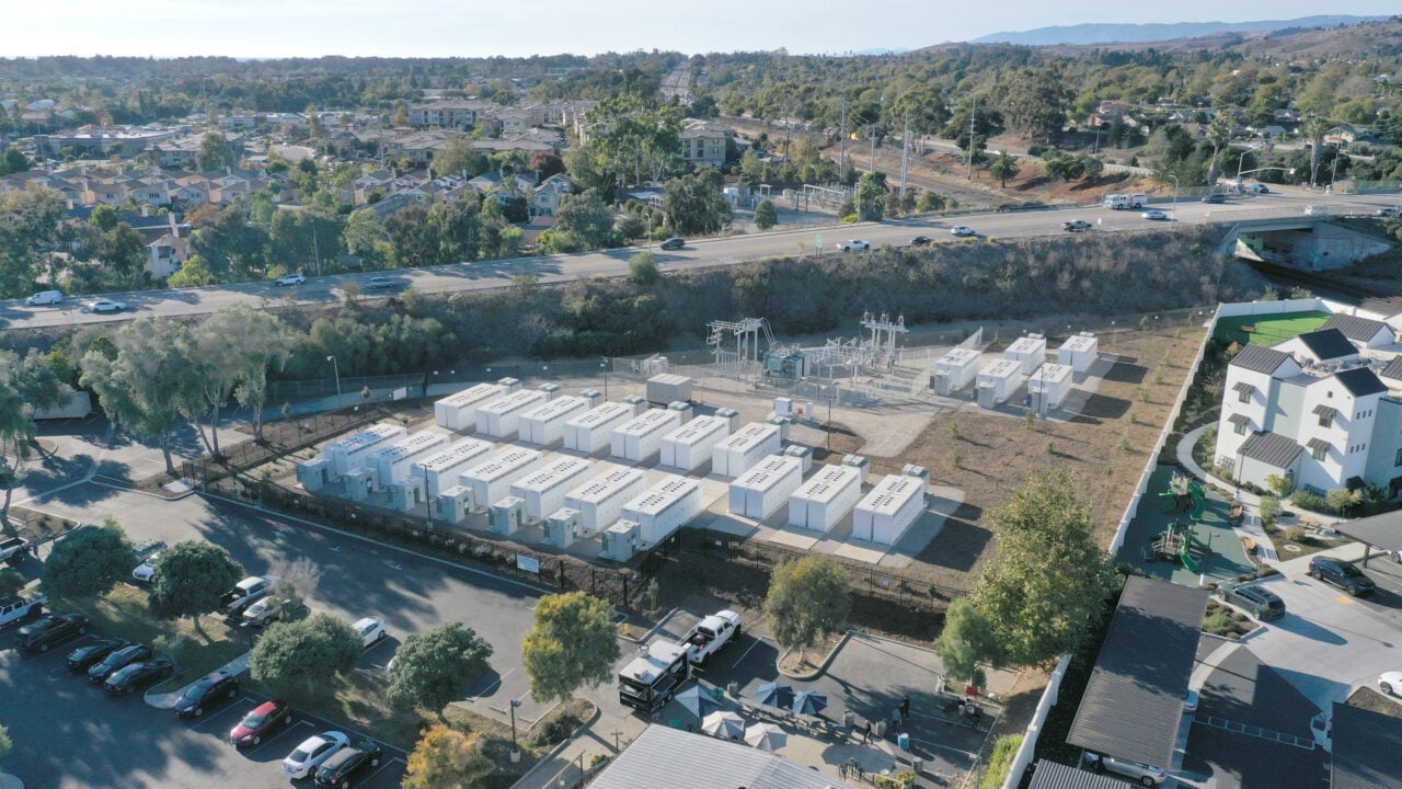 Large scale battery energy storage system containers installed at a utility site under a blue sky.