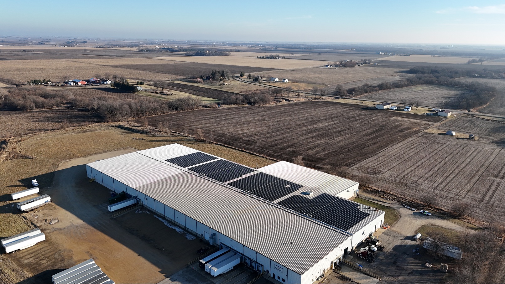 Large-scale rooftop solar array on a manufacturing facility under a clear sky.