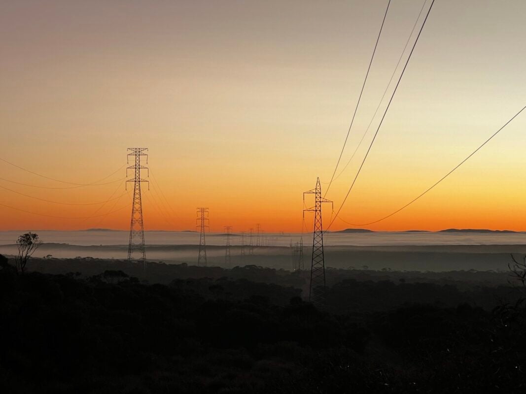 Aerial view of large-scale solar farm with industrial facilities in the background