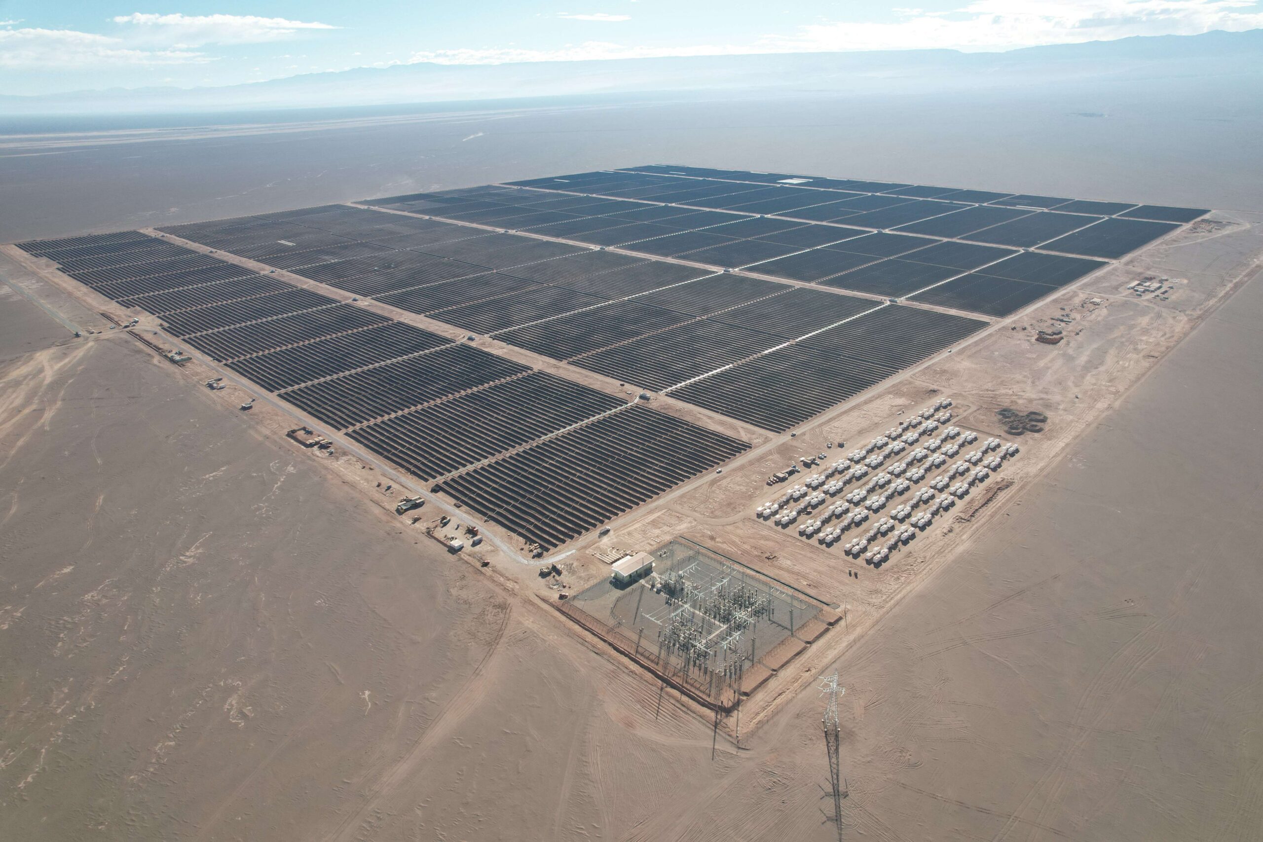 Large scale solar farm in Spain with battery storage containers being installed nearby.