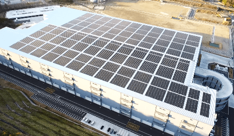 A massive logistics warehouse roof covered in thousands of solar photovoltaic panels.