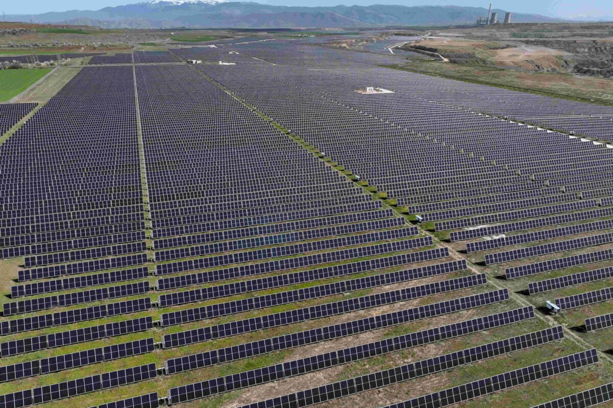 Large scale utility solar farm with thousands of rows of PV panels stretching to the horizon
