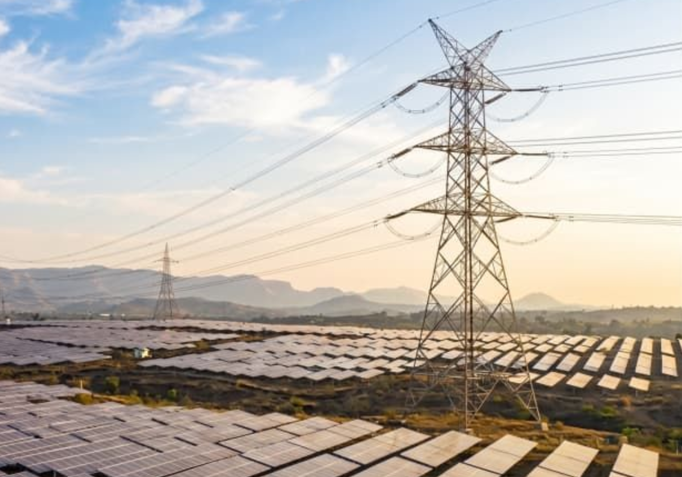 Electric grid towers in Spain against a sunset, symbolizing the need for grid stability and demand response.