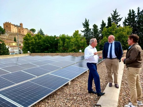 Aerial view of historic Spanish town rooftops with municipal solar panel installation project planned.