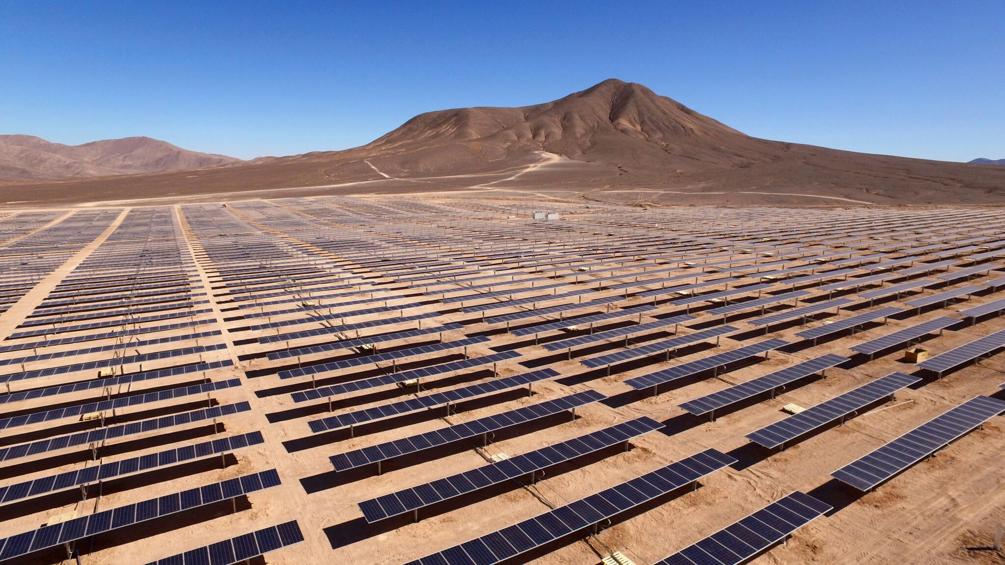 Large scale battery energy storage containers situated next to a utility-scale solar farm in rural Spain.