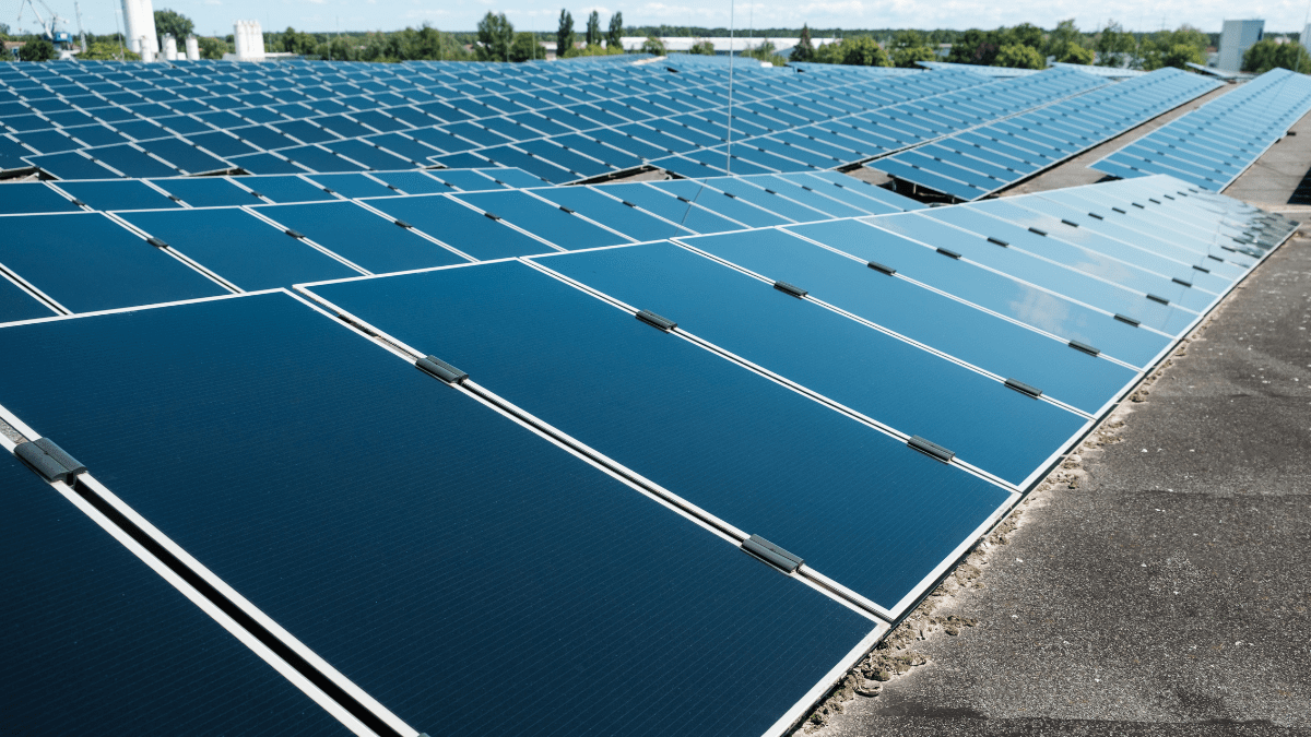 Aerial view of a large sports stadium with a massive rooftop solar panel installation.