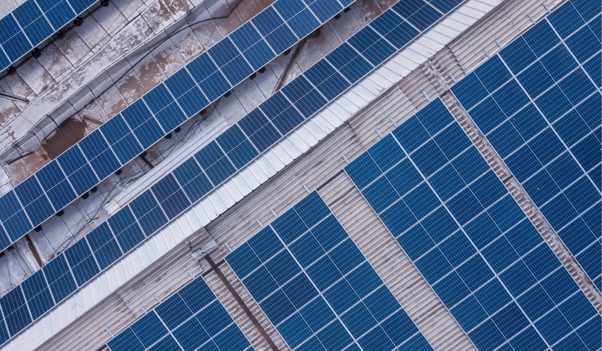 A massive stack of solar panels being unloaded at a busy tropical shipping port.