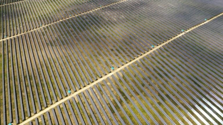 Aerial view of a massive utility-scale solar farm stretching across a dry, arid landscape.