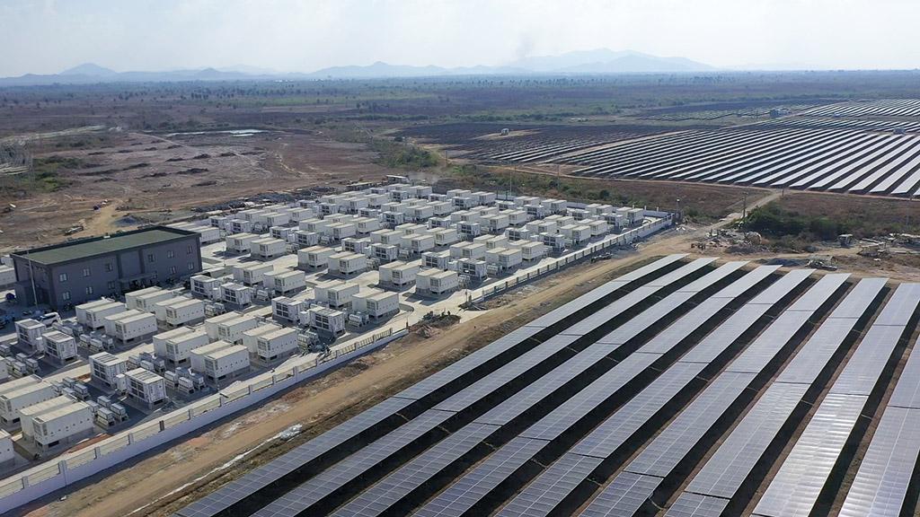 Large scale battery energy storage system containers in a field with power lines in the background