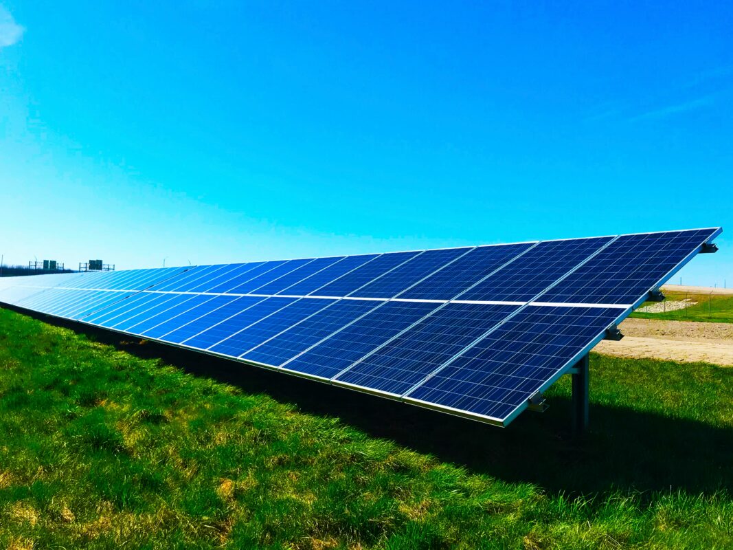 A large-scale solar farm with battery storage containers under a clear blue sky