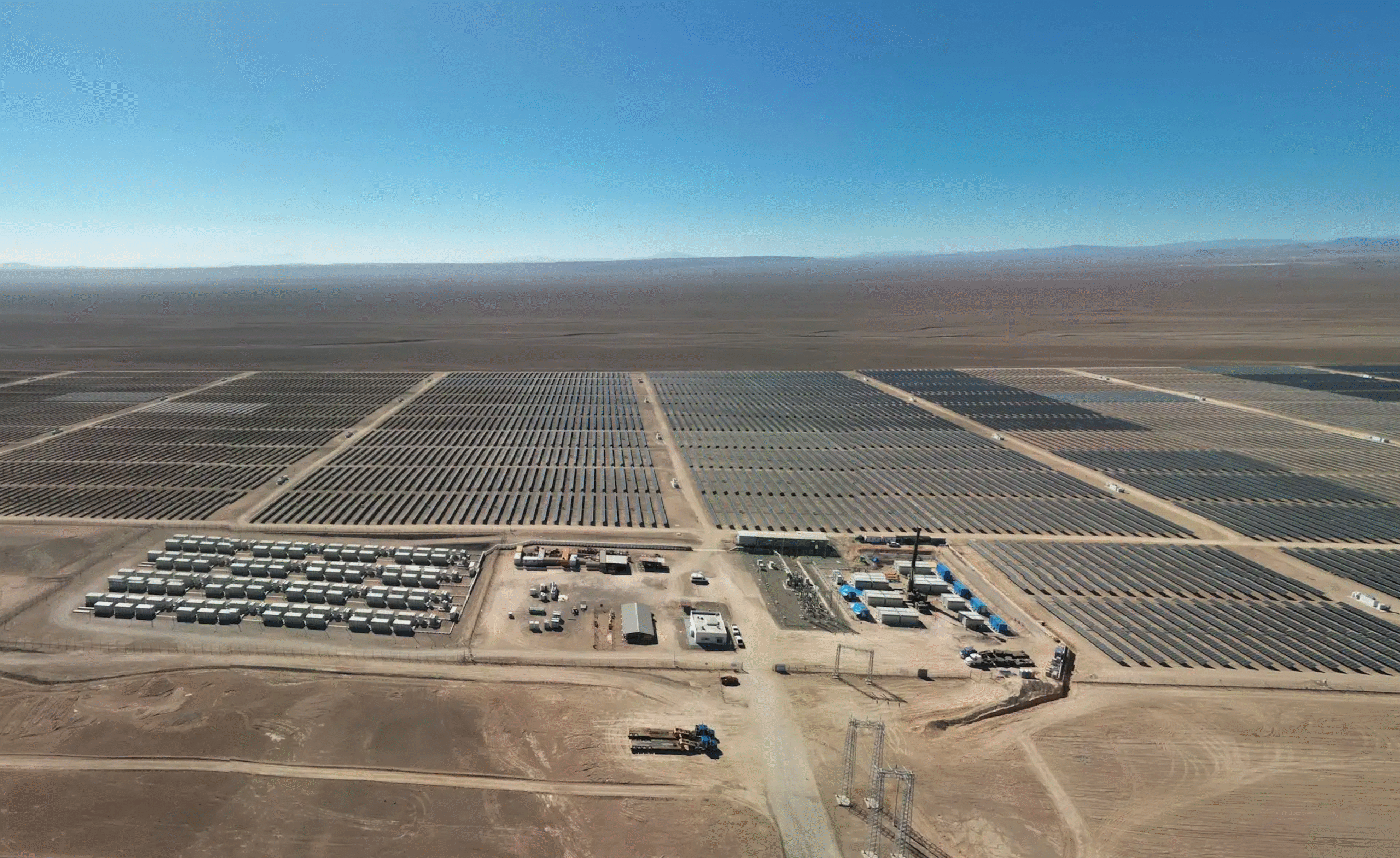 Large scale solar farm with trackers and battery storage containers in the background