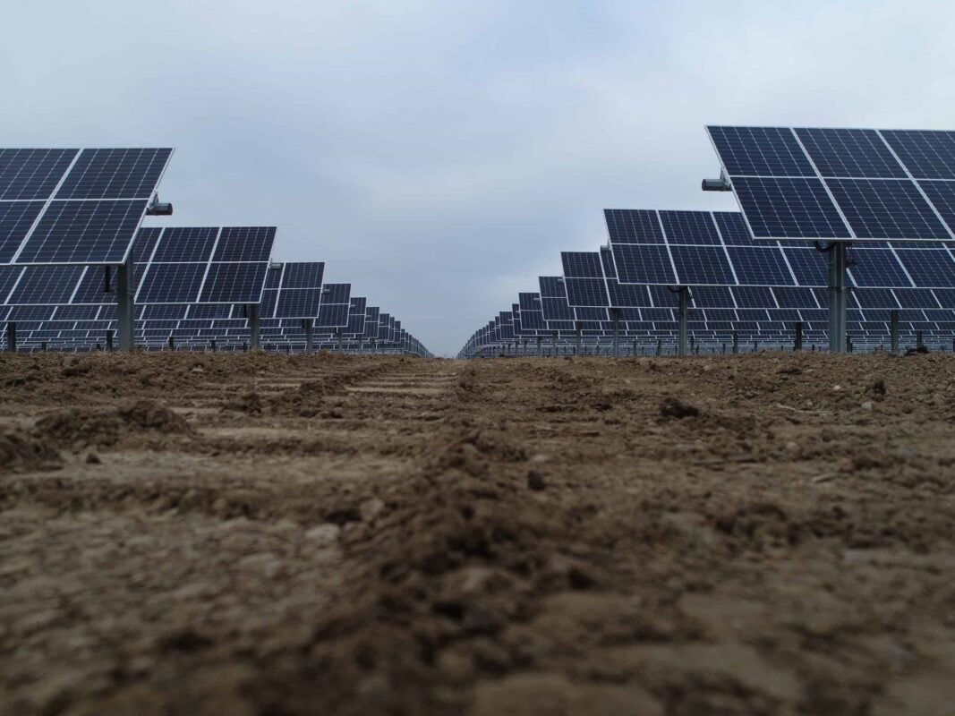 Aerial view of a large-scale solar photovoltaic power plant with rows of panels in a field.