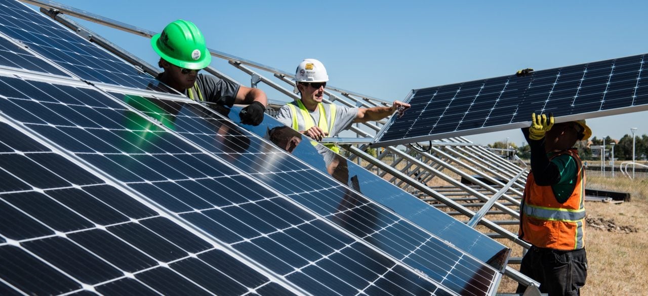 A modern solar module manufacturing line with robotic arms and blue PV cells.