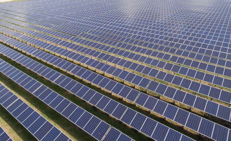 Large scale solar farm under construction with workers installing panels in a high-growth region.