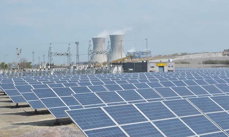 Aerial view of a large-scale solar panel farm in a flat, arid landscape.
