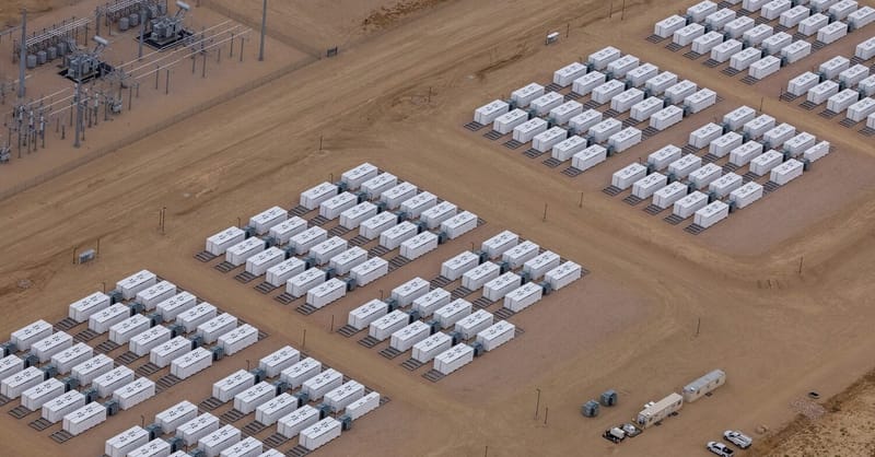 A large-scale grid energy storage facility with rows of lithium-ion battery containers under a clear sky.
