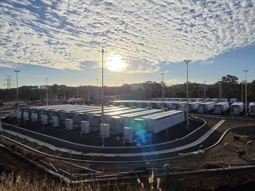 Aerial view of a large-scale battery energy storage system with white containers and electrical infrastructure.