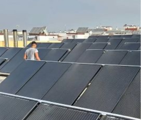 Aerial view of a Spanish municipal building with newly installed solar panels on a flat roof.