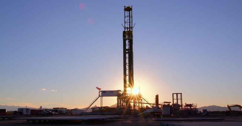 A drilling rig at a geothermal energy site against a clear blue sky