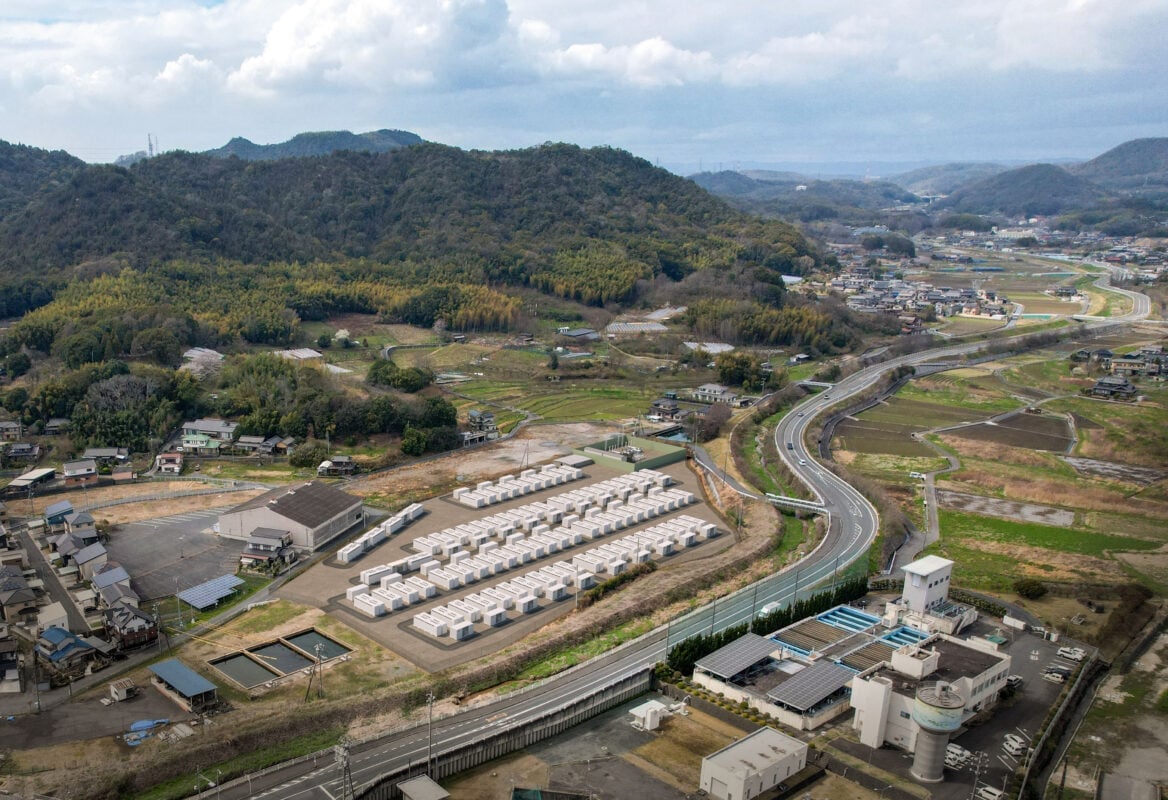A large-scale battery energy storage system facility with industrial shipping containers and transformers.