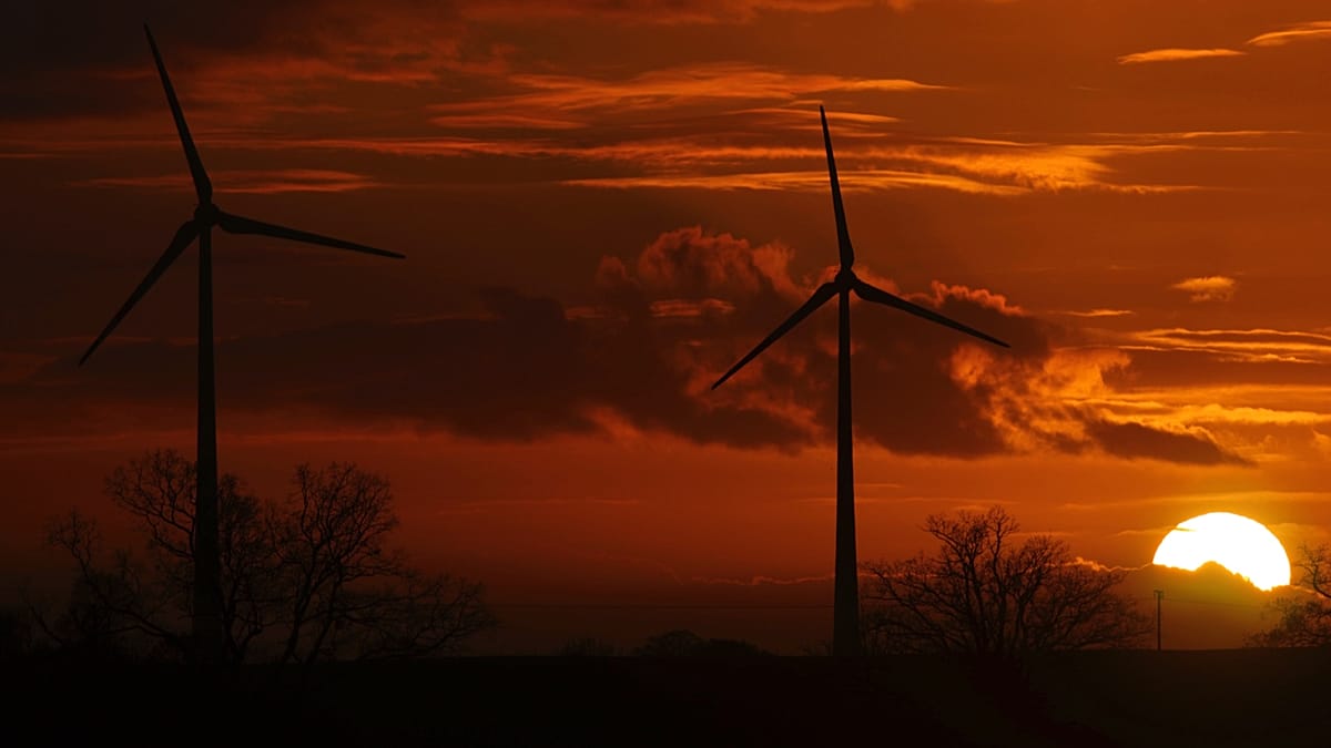 A modern European electrical substation integrated with solar panels and wind turbine infrastructure.