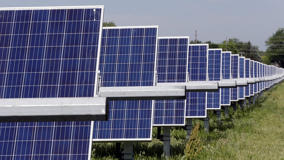 A row of high-power commercial solar inverters installed on a concrete pad.