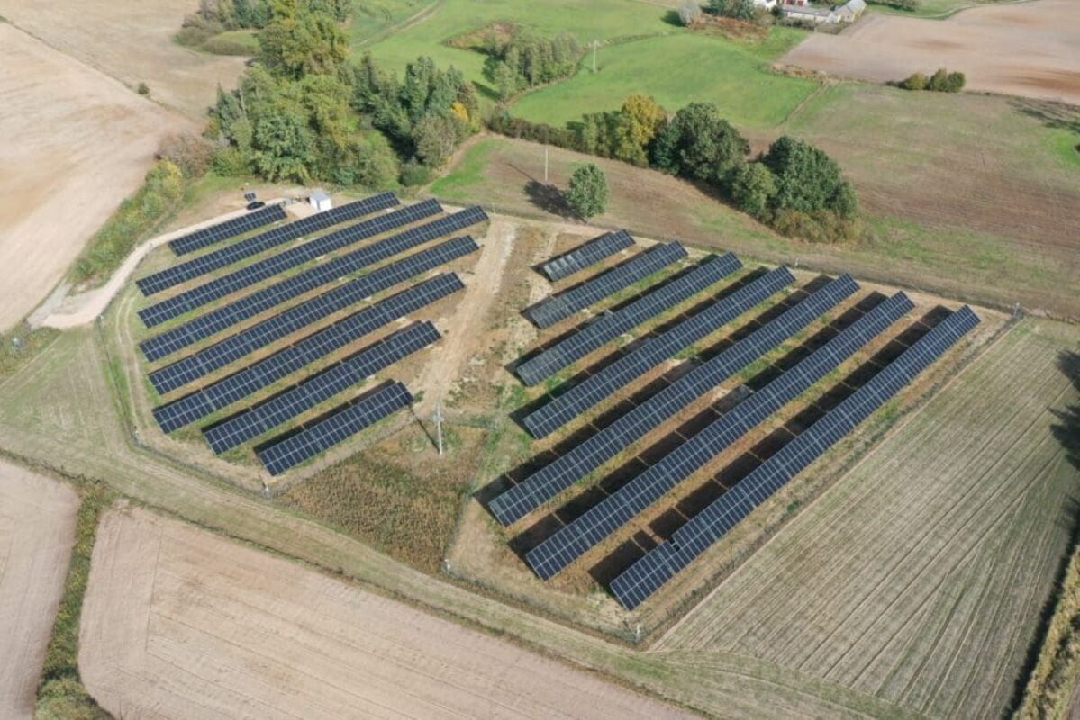 Aerial view of solar panel installation in a field with construction equipment nearby.