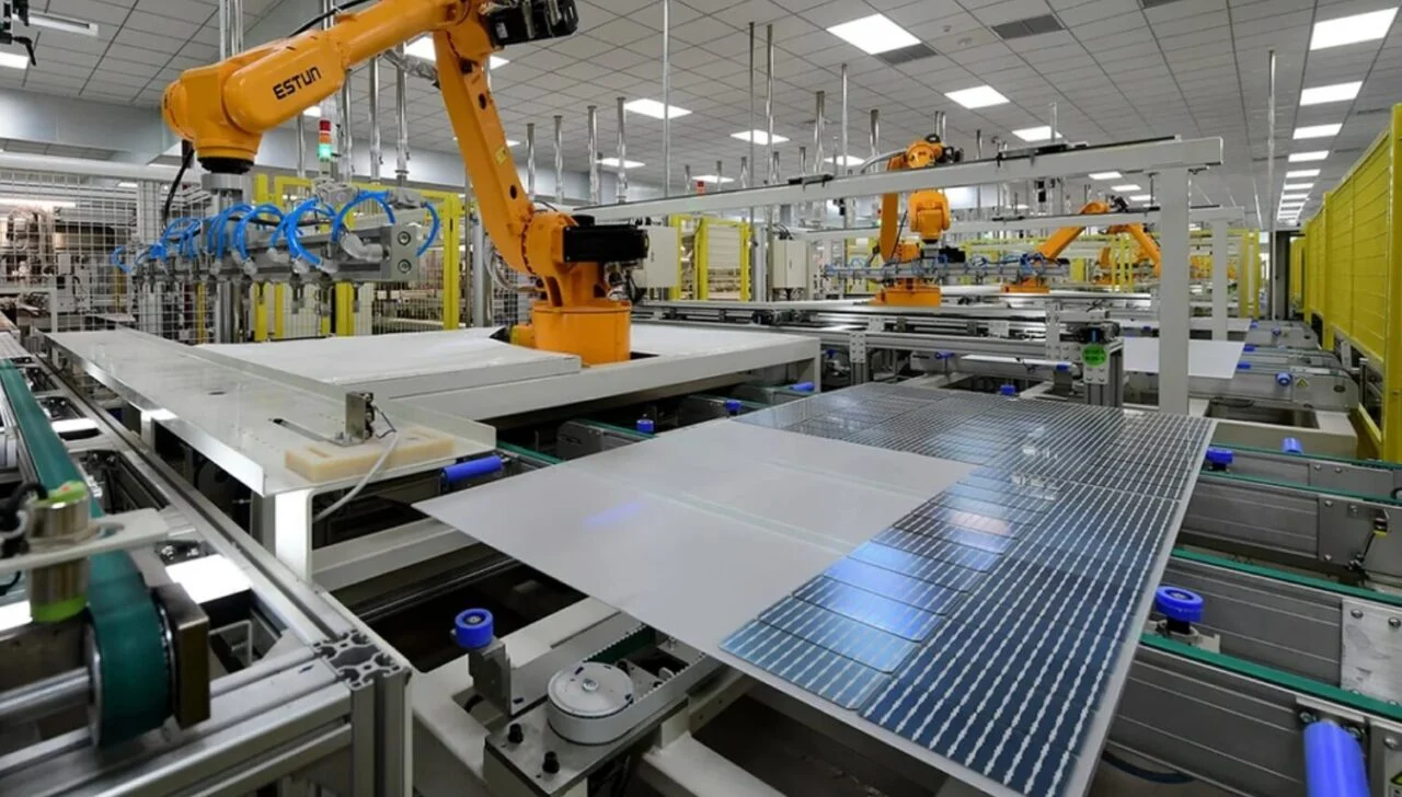 Aerial view of a small-scale manufacturing warehouse with solar panels on the roof and industrial equipment.