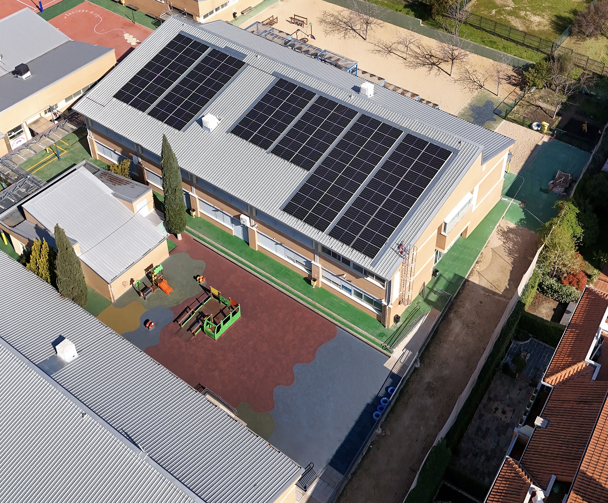 Solar panels being installed on a Spanish school rooftop with workers securing mounting systems