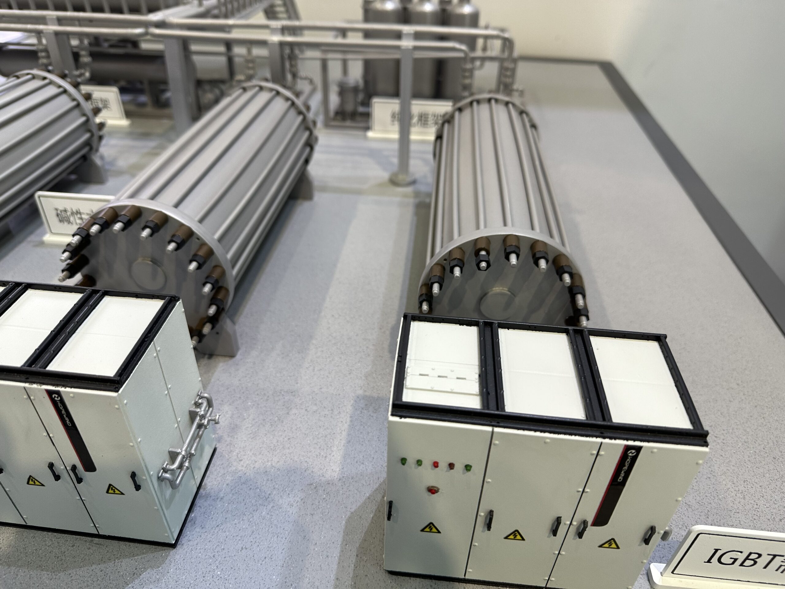 Industrial green hydrogen electrolyzer unit connected to a solar farm under a bright sun.