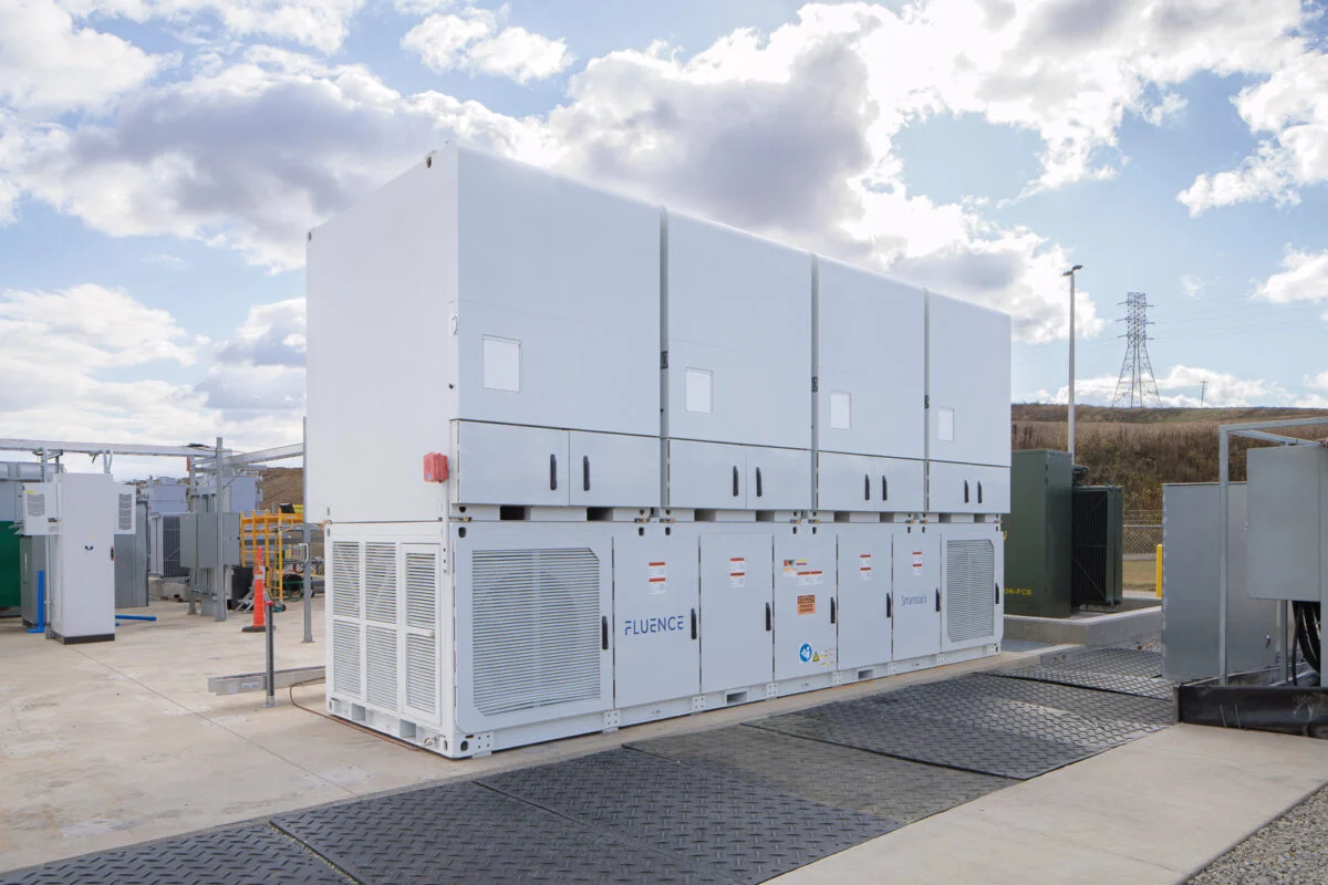 A massive utility-scale battery storage facility with white Fluence Cubes under a clear blue sky.