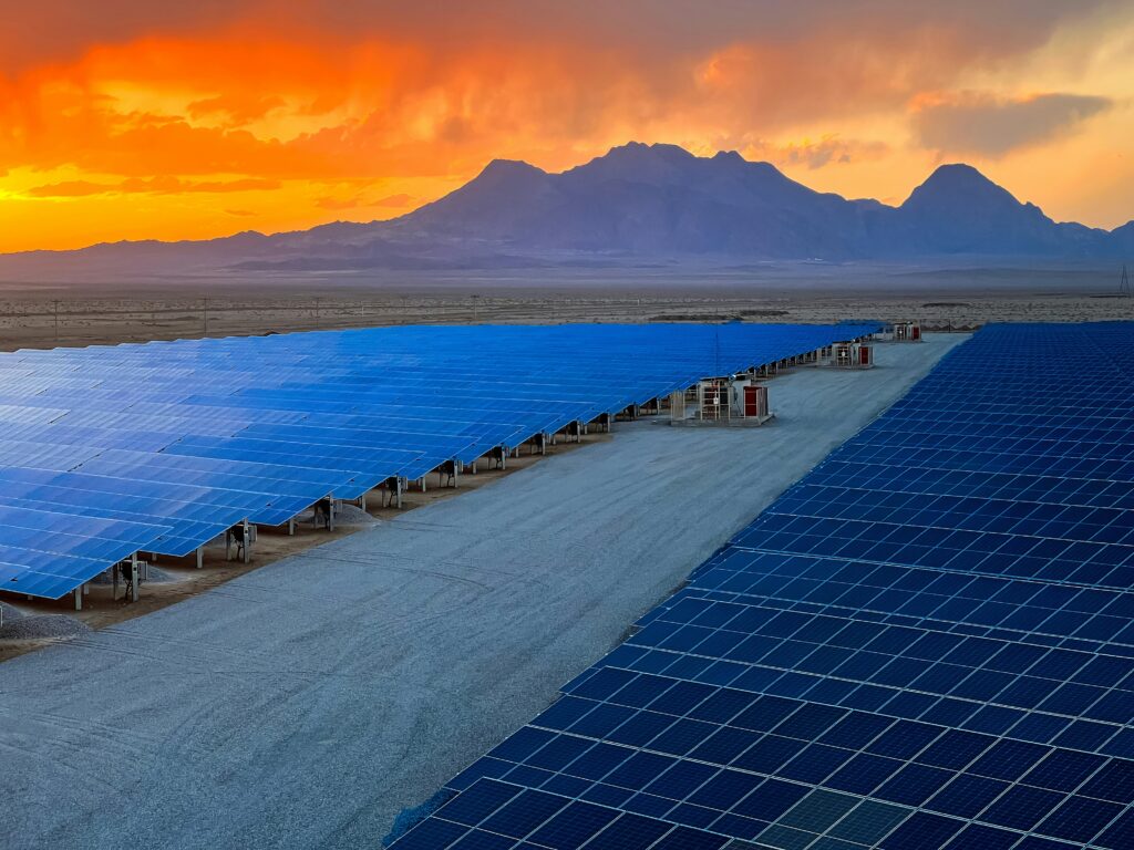 Solar panels at an industrial facility with nuclear cooling towers in the background