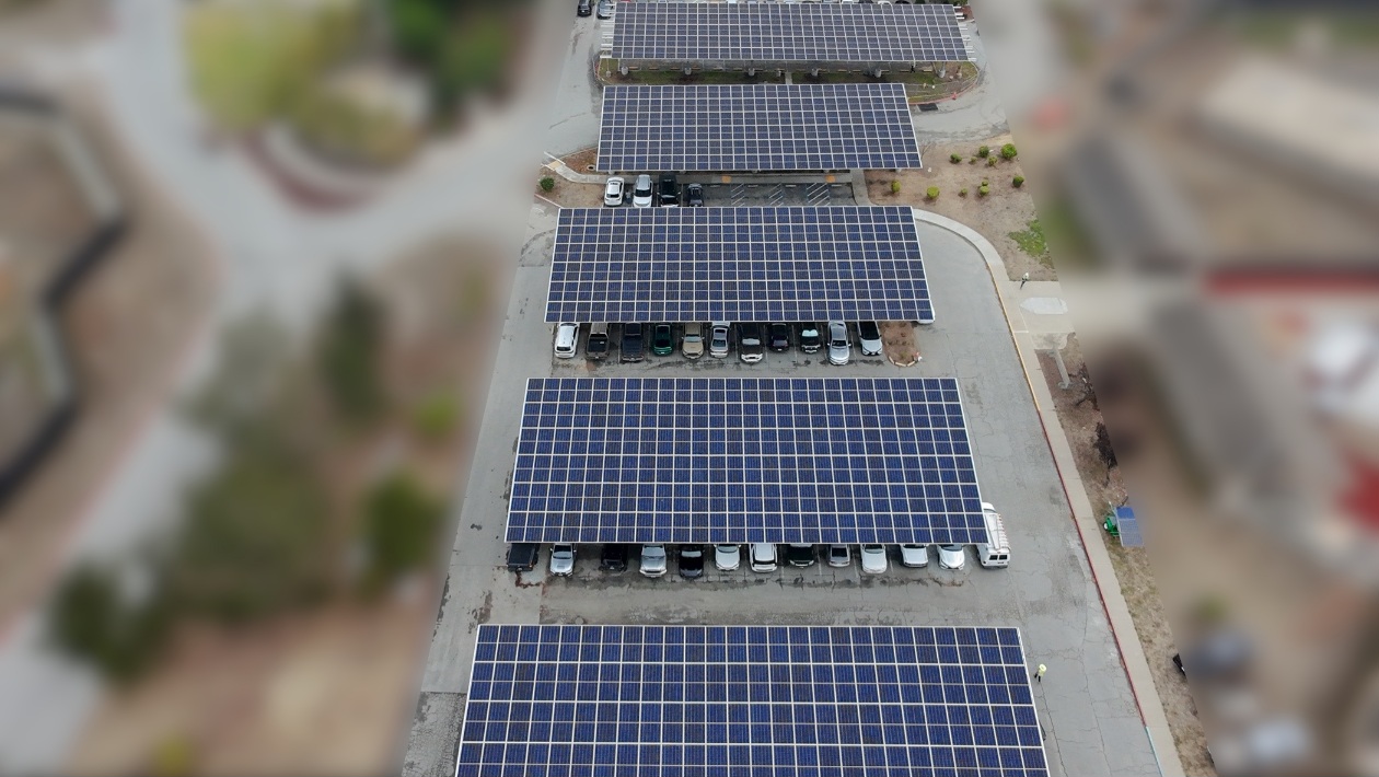 Modern solar carport structure with integrated battery storage installation in a parking lot.