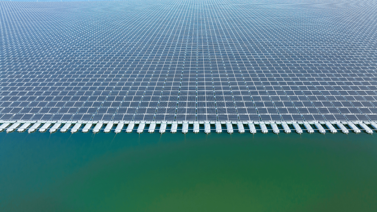 Aerial view of a large-scale floating solar array on a reservoir with blue water.