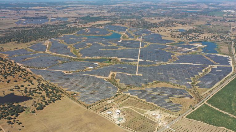 Aerial view of a large-scale solar farm with integrated battery energy storage containers in Portugal.