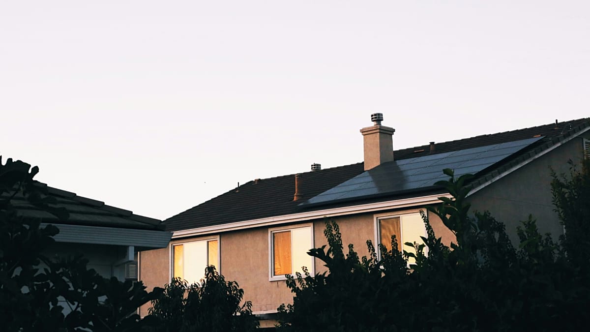 A modern black solar panel mounted on a high-rise apartment balcony railing in a European city.