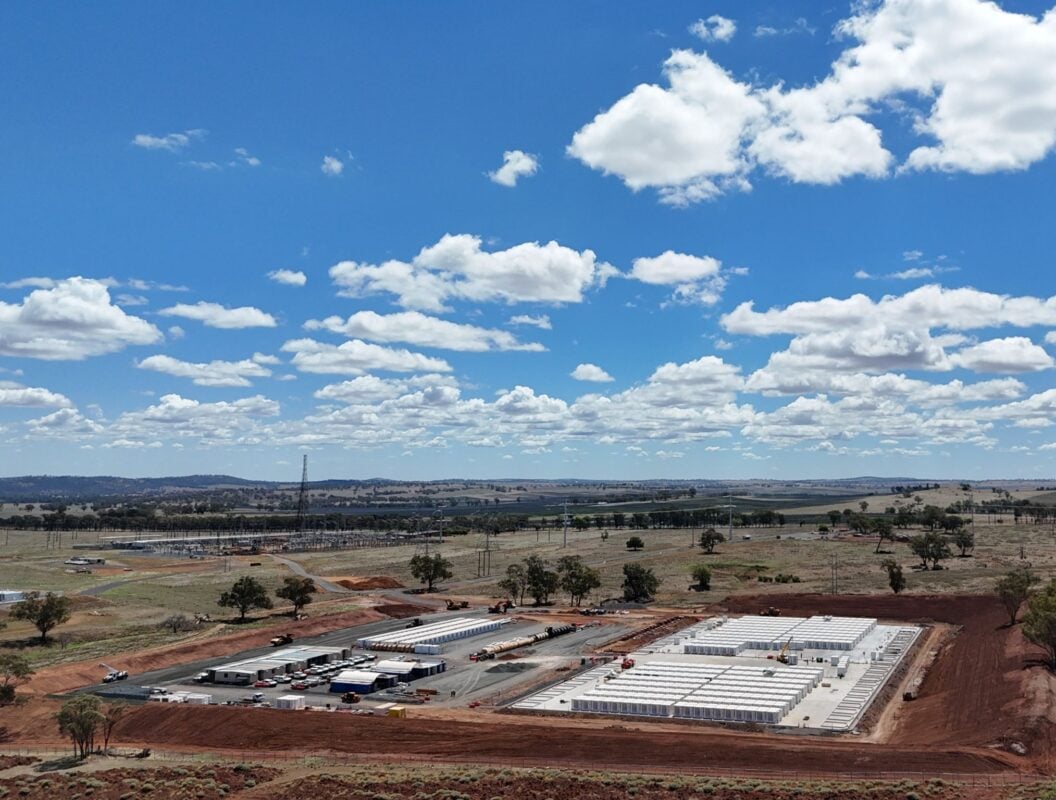 A massive field of Fluence Gridstack battery enclosures under a clear blue sky during installation.