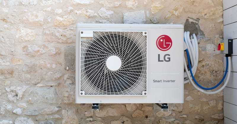 A modern heat pump unit installed next to a residential solar inverter and battery system.