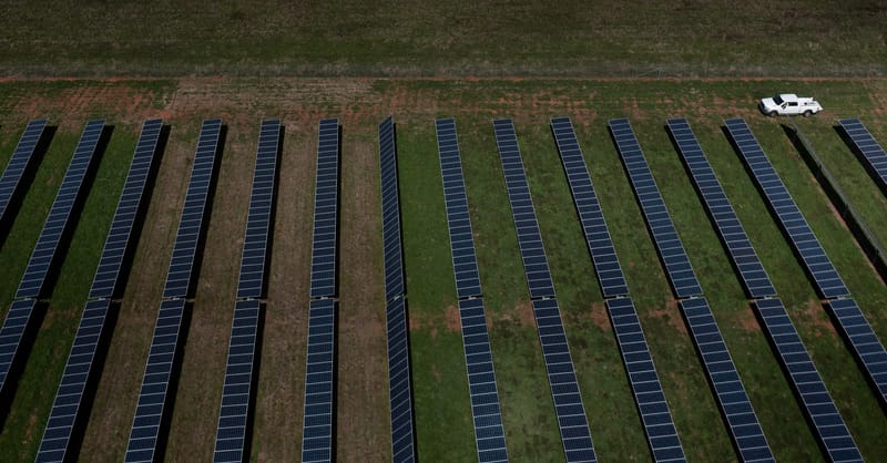 A massive, sleek data center complex surrounded by a sprawling utility-scale solar farm.