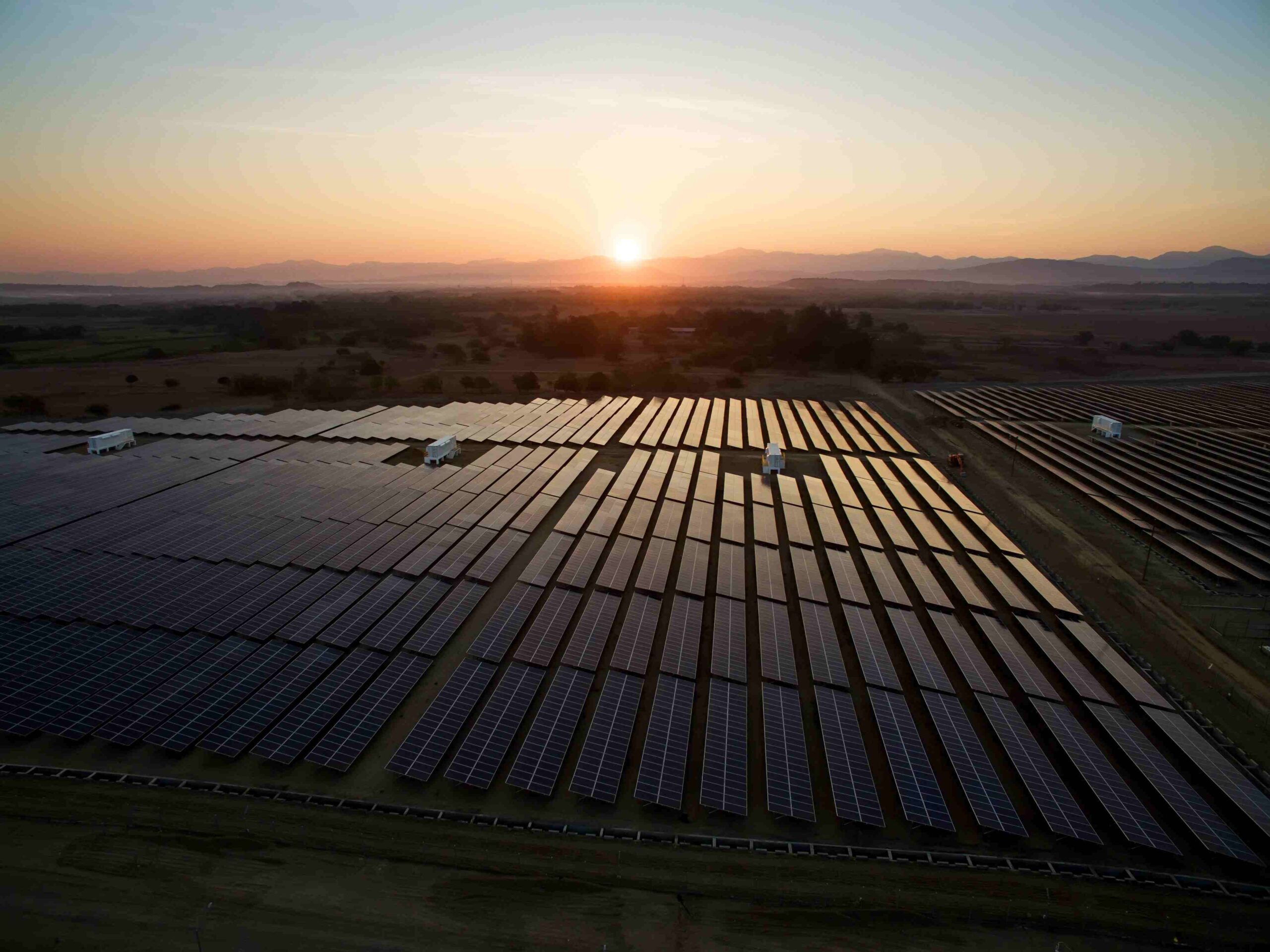 Aerial view of a large-scale solar farm construction site under sunny skies.