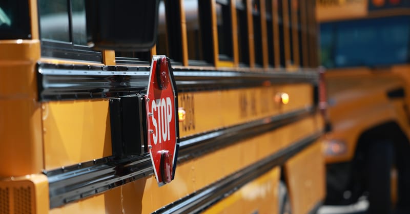 A row of yellow electric school buses parked at a charging station facility.