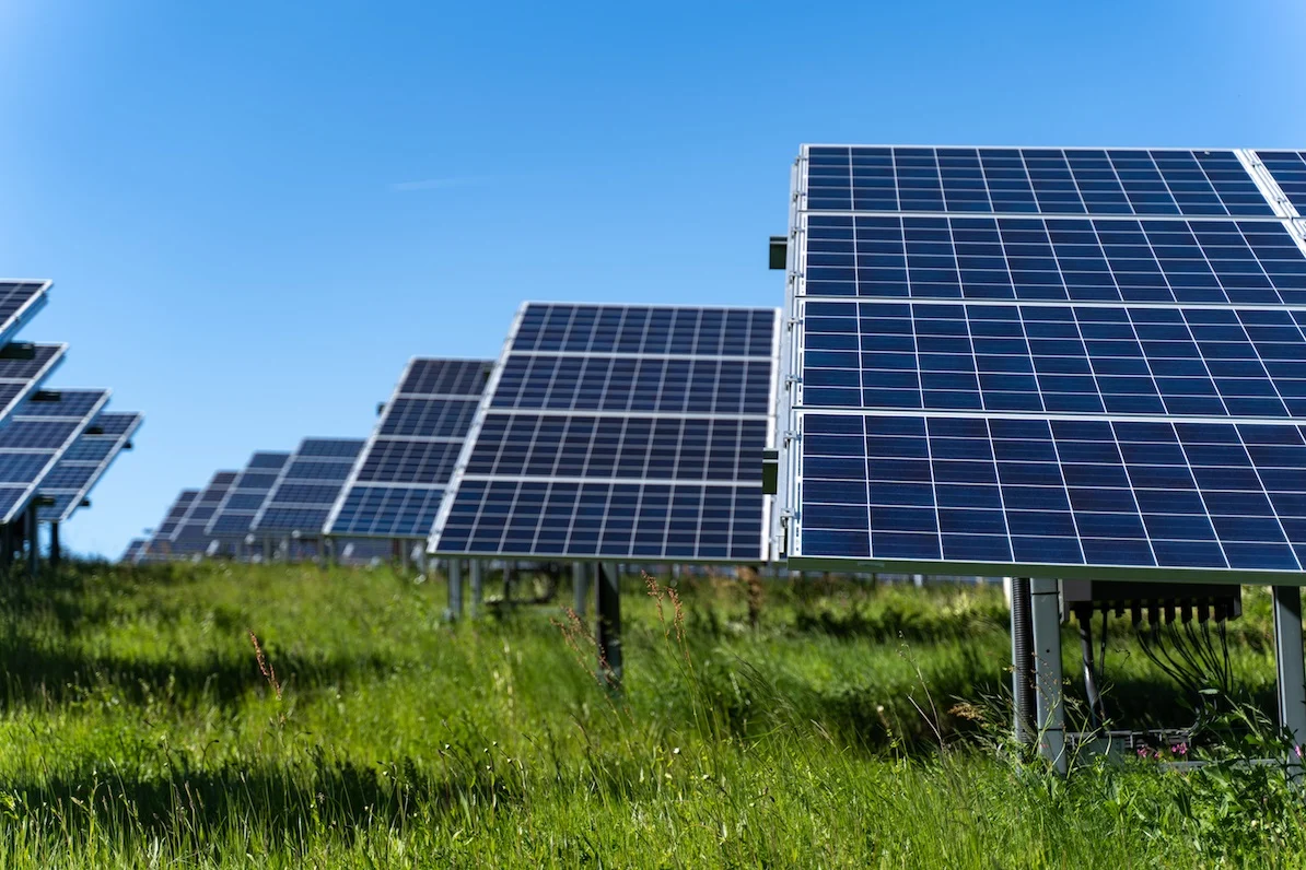 Large scale solar farm construction in Germany with heavy machinery and rows of mounting structures.