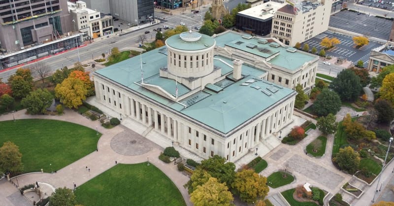 A utility-scale electrical substation next to a residential solar installation on a rural landscape.