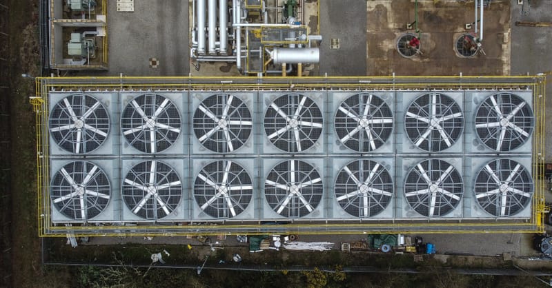 A futuristic geothermal power plant site with solar panels installed in the surrounding fields.