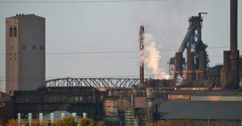 Workers inspecting steel coils in a modern, decarbonized green steel manufacturing facility